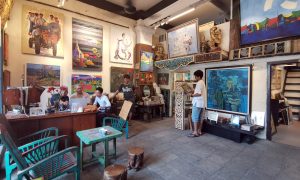 A picture of people inside Pansodan Art Gallery, with many paintings on the wall